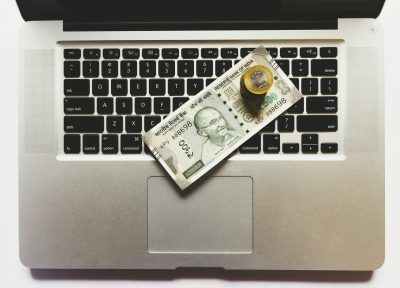 cash and a bitcoin on a laptop